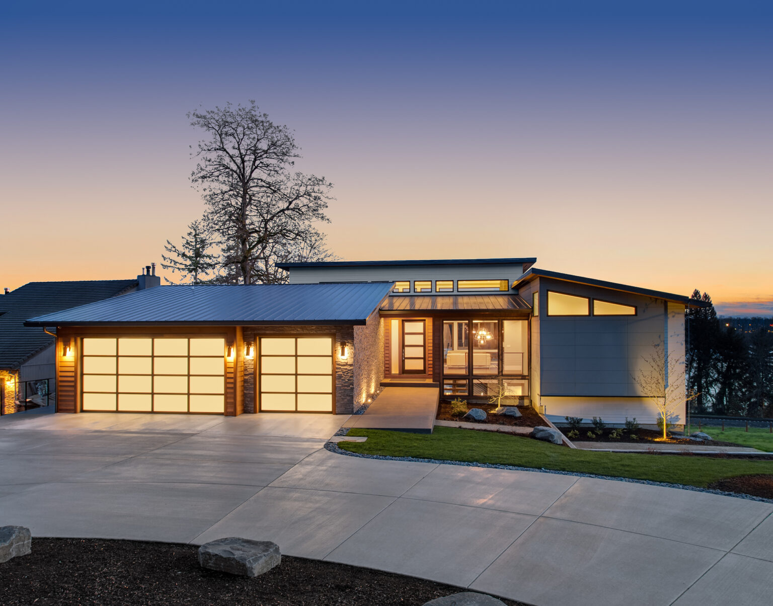 Modern single-storey home with lit windows at sunset