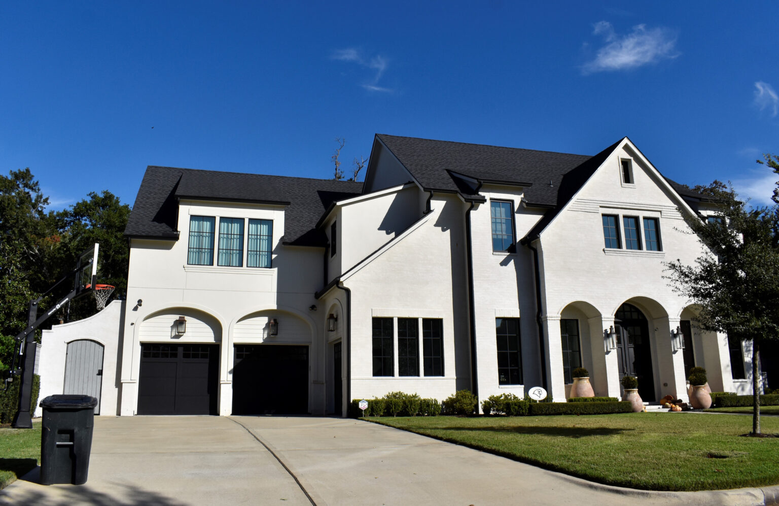 Large white-brick home with dark roof and trim